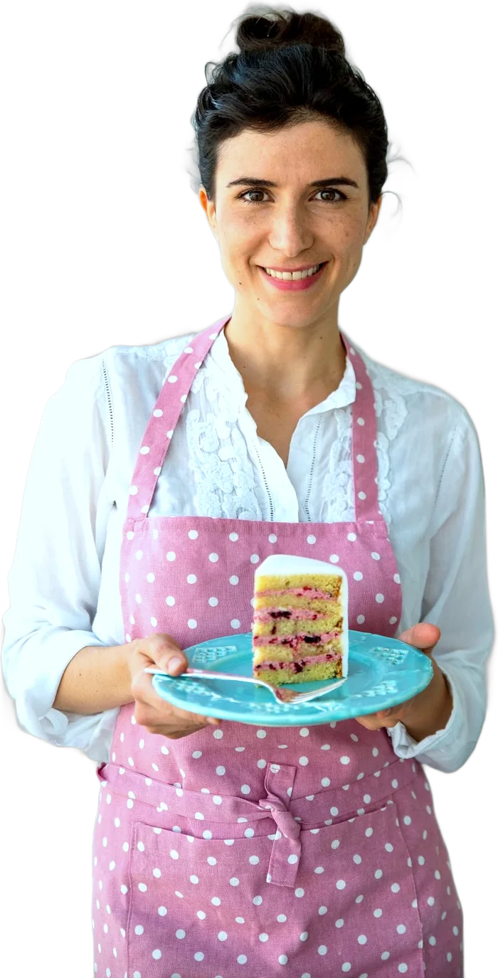 Otávia Sommavilla de avental rosa, segurando uma fatia de bolo